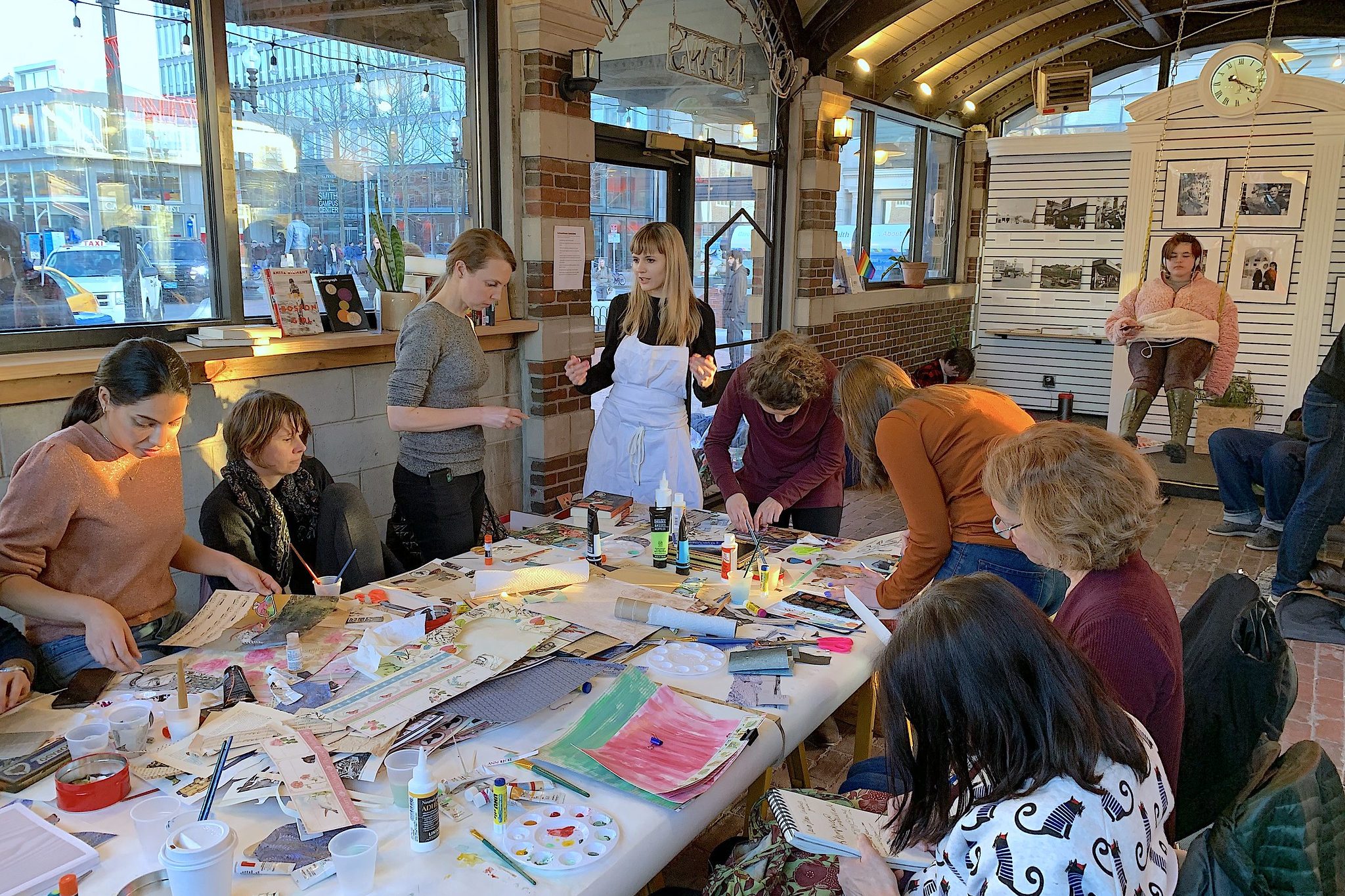 People paint and gather around a table for a workshop in the Kiosk