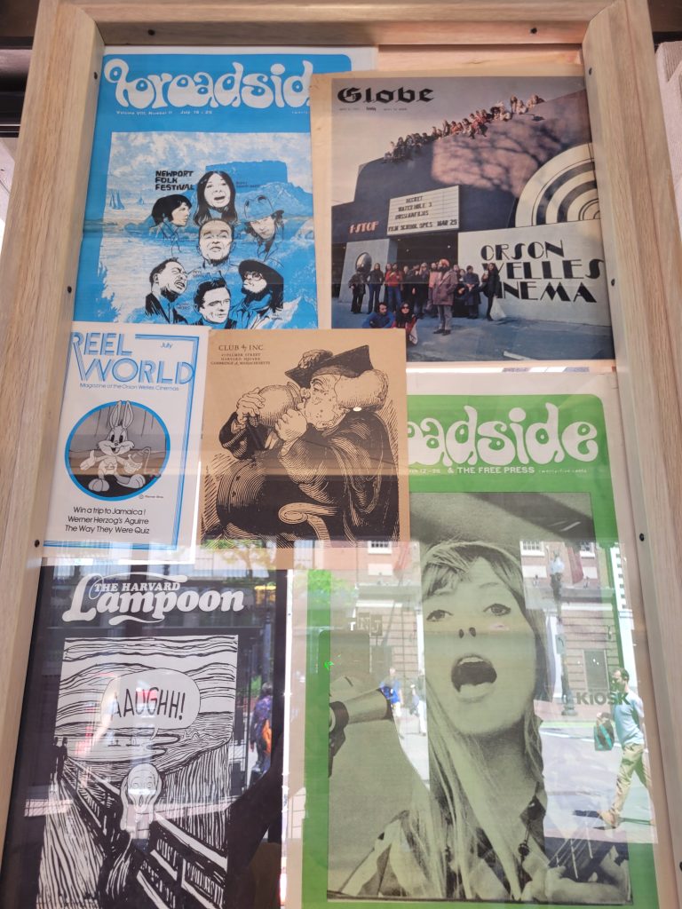 Colorful front pages from old newspapers hang in a frame as part of the Cambridge: Then and Now exhibition