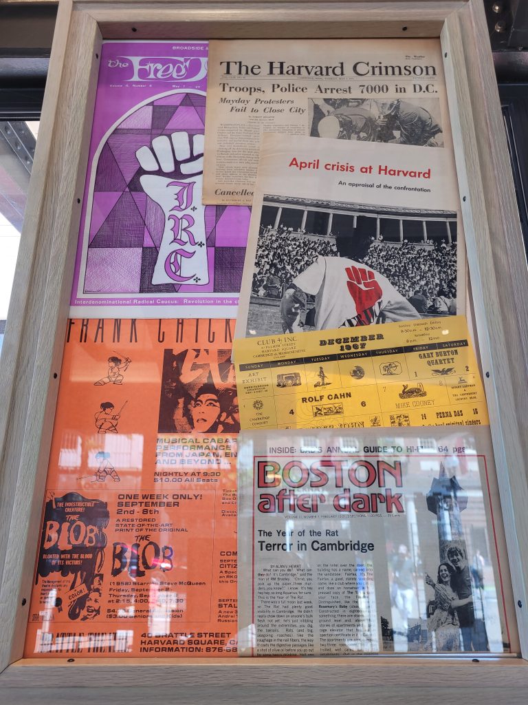 Colorful front pages from old newspapers hang in a frame as part of the Cambridge: Then and Now exhibition