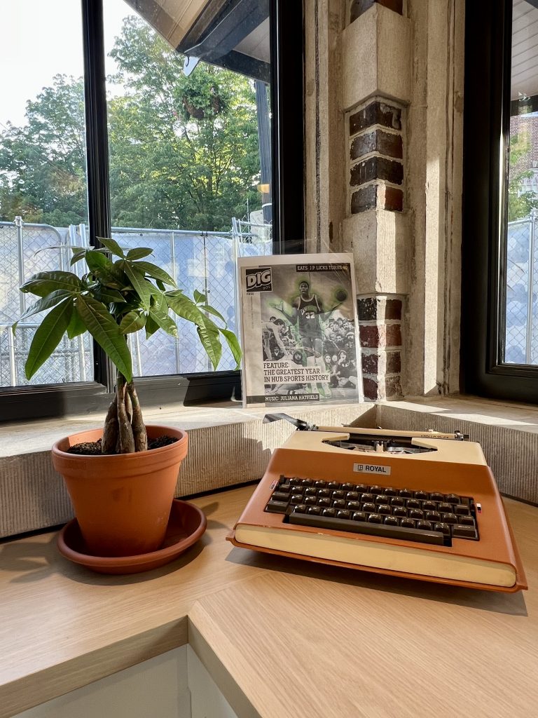 An old typewriter and old newsprint copy sit on display at the KiOSK alongside a money tree plant