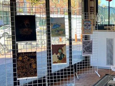 graphic posters hang on white wire grids in front of the glass front doors of the KiOSK